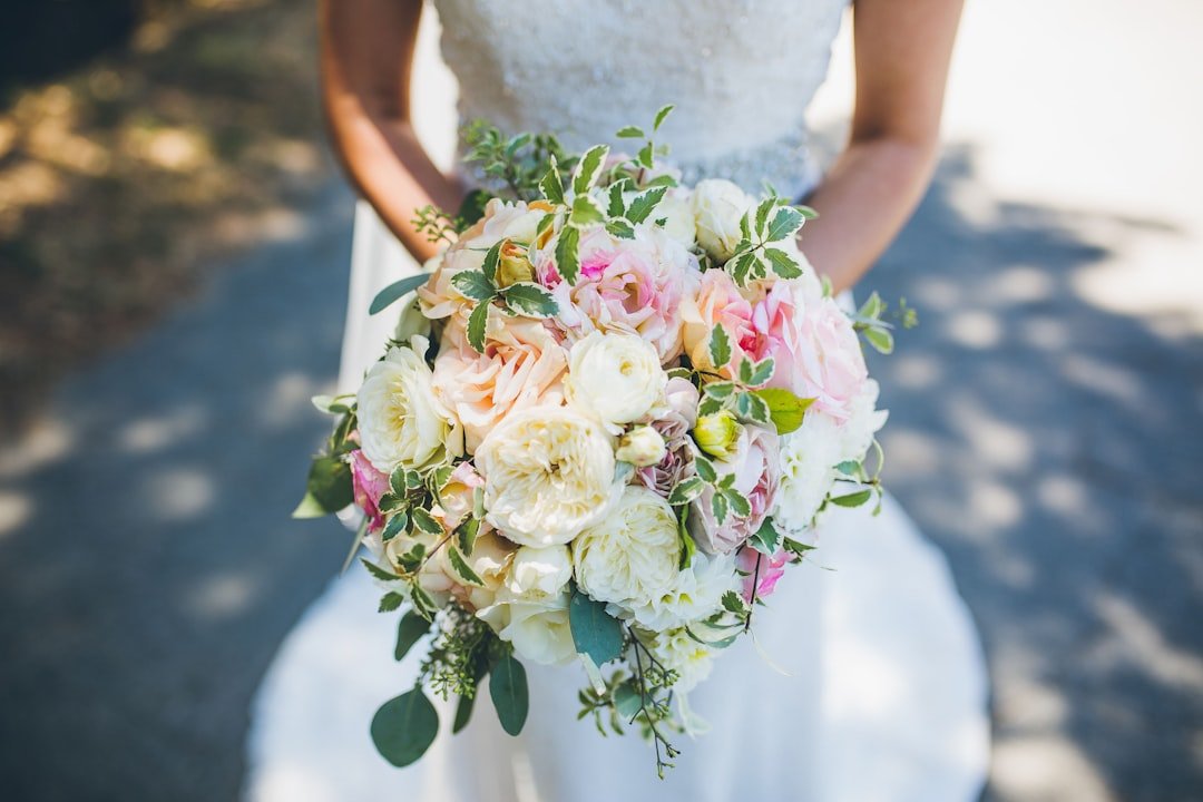 Bride in white wedding dress holding a bouquet of white and pink roses